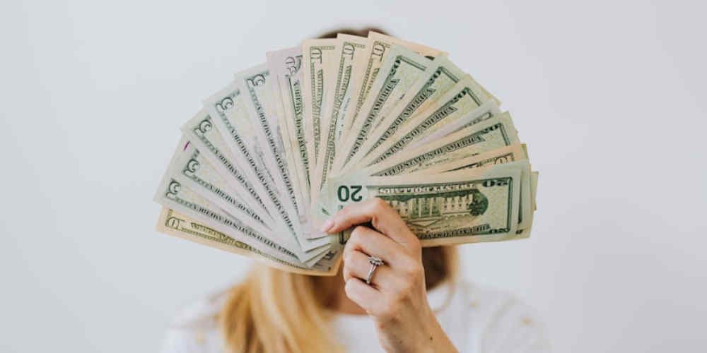 woman hiding her face with gambling money