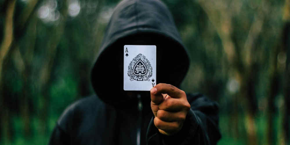 hooded man plays card game like snap