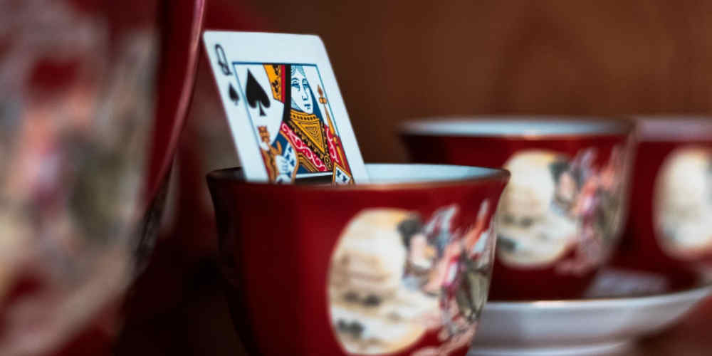 stock market vs blackjack repesented with a playing card in a porcelain cup